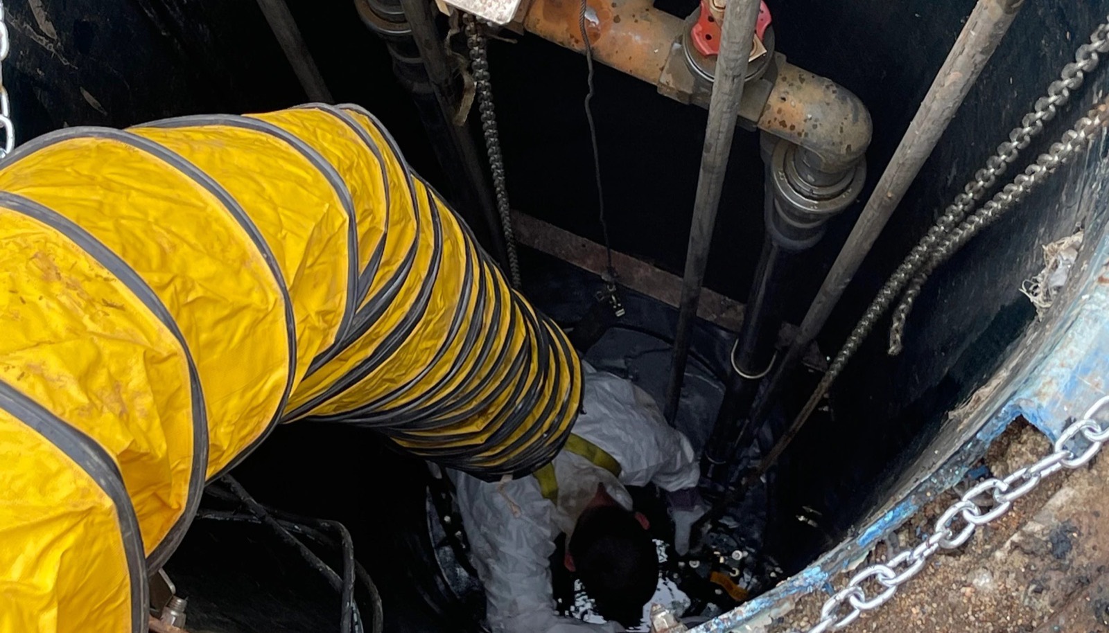 An Okie technician working on a sewer line in a tight space
